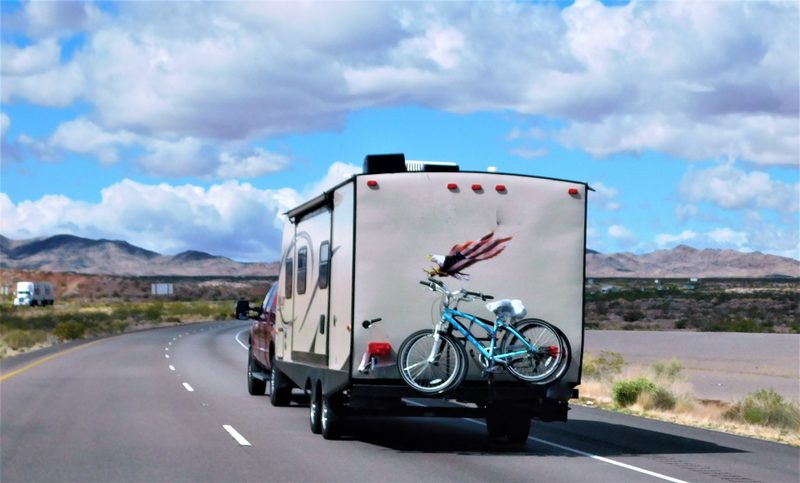 Travel trailer being towed down a desert highway with bikes mounted on the back
